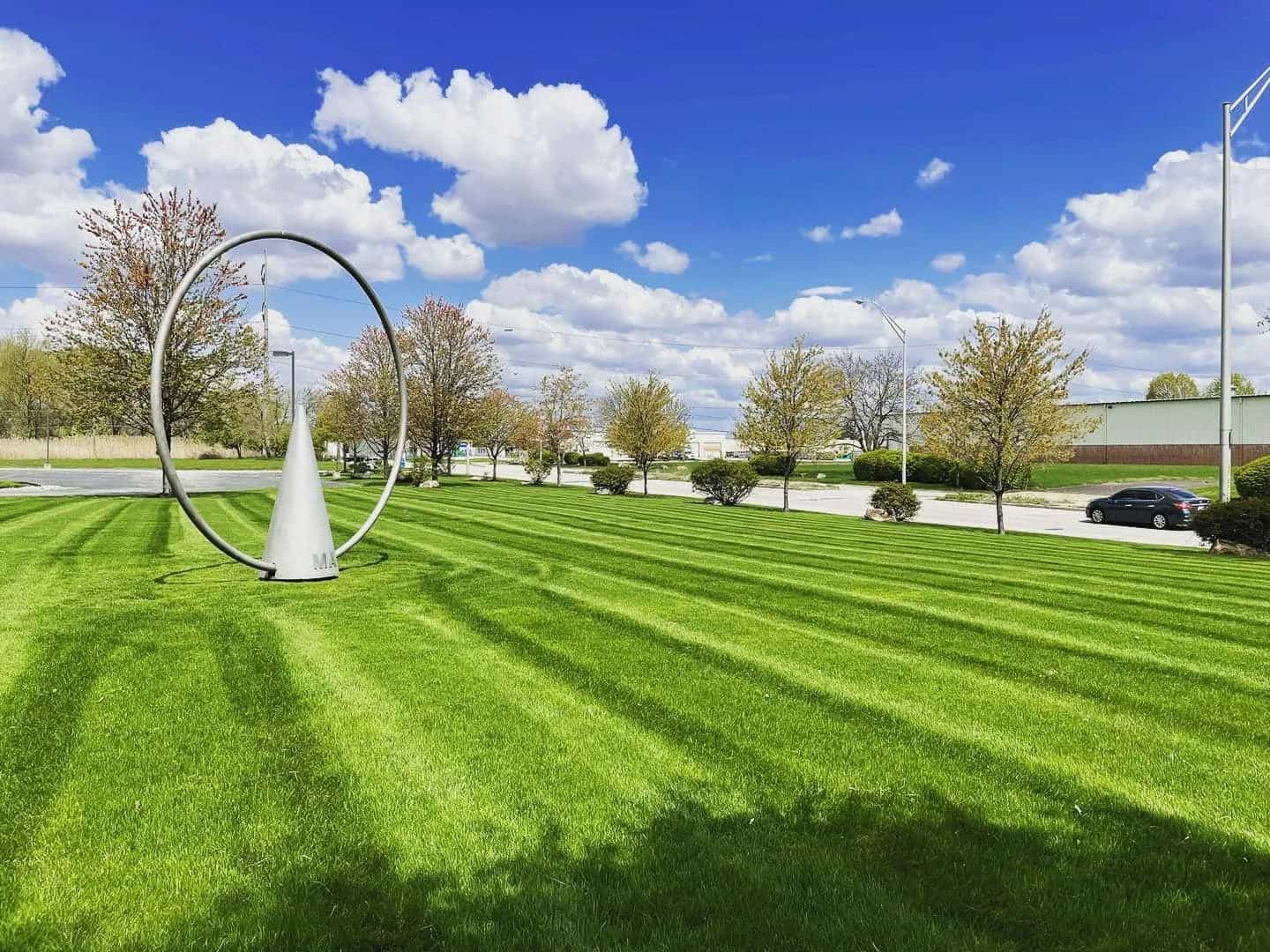 A freshly striped green lawn along the sidewalk and trees lining the street.