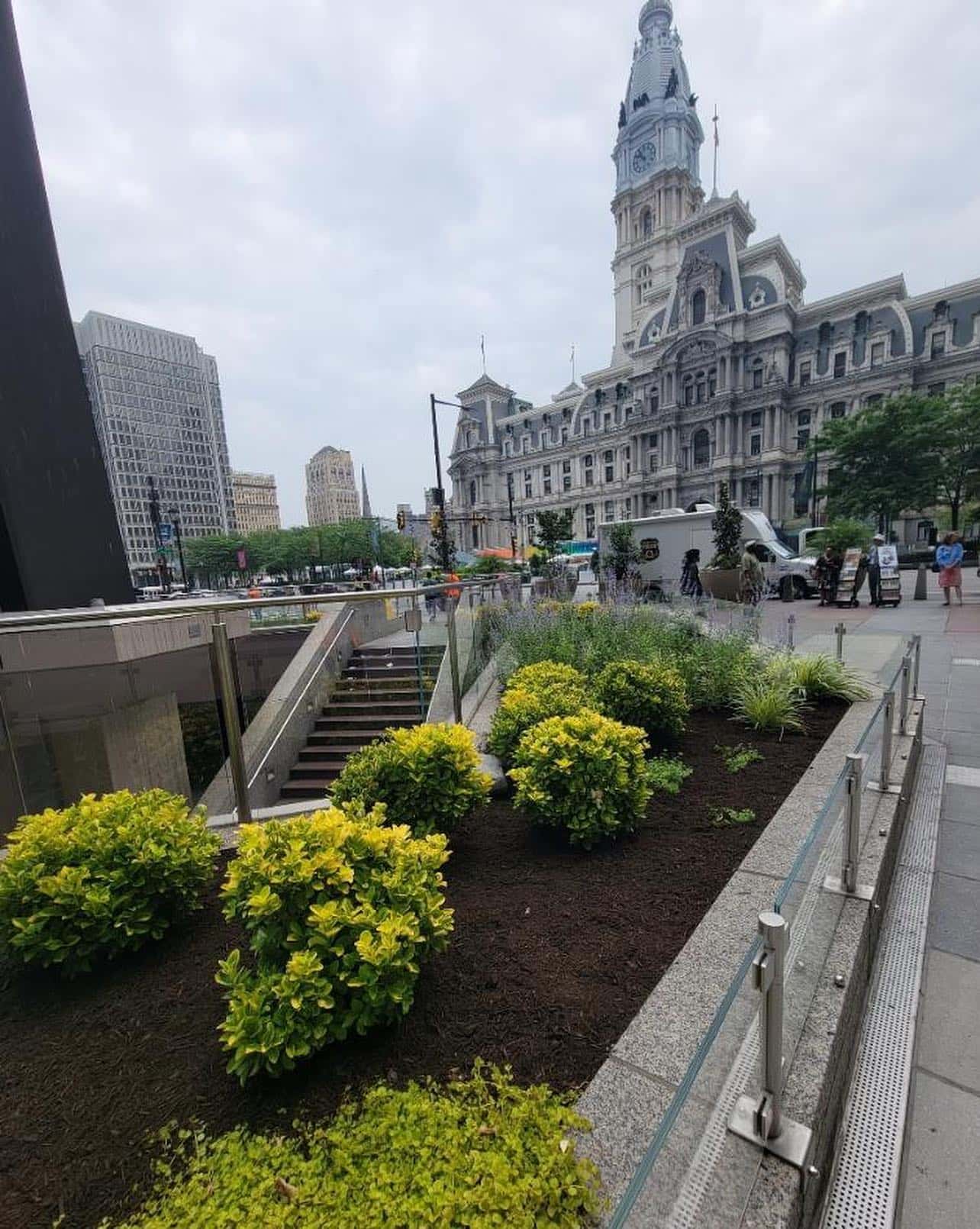 City hall building with a clock tower, surrounded by vibrant flowers and well-maintained landscaping.