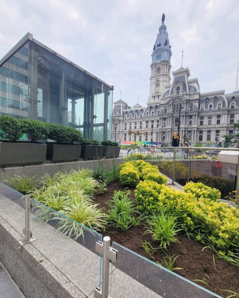 City hall building with a clock tower, surrounded by vibrant flowers and well-maintained landscaping.