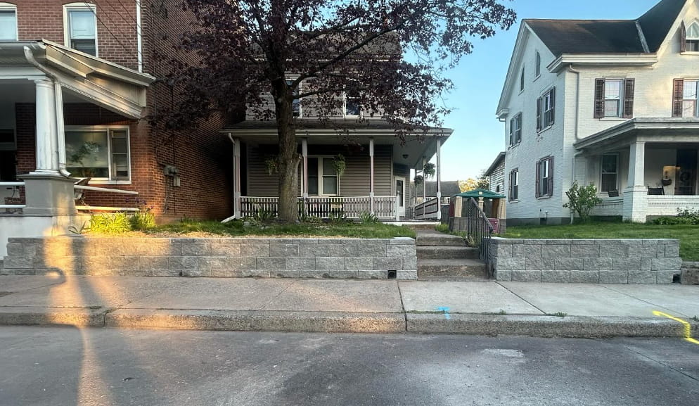 Concrete retaining wall with front yard steps and walkway in front of residential homes along a city street